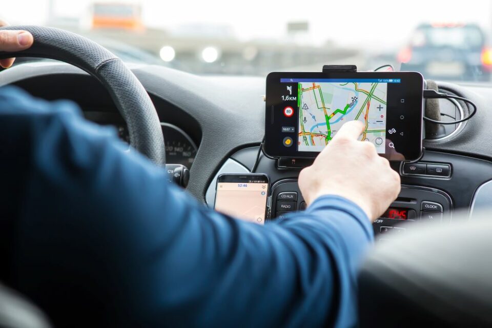 Un homme est assis dans sa voiture, utilisant le GPS pour se rendre au travail, illustrant la mobilité professionnelle quotidienne.